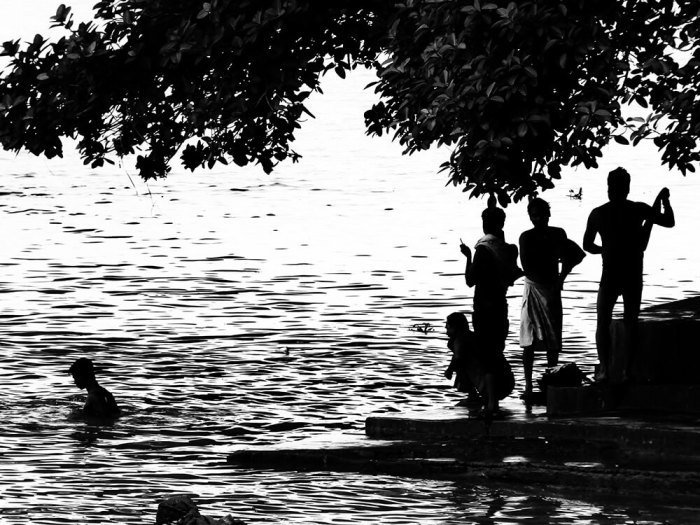 Men bathing on steps and underneath a tree in a the Hooghly River